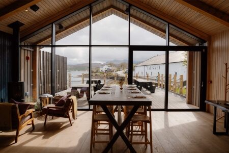 Dining table beside floor-to-ceiling windows overlooking Talisker distillery and the loch
