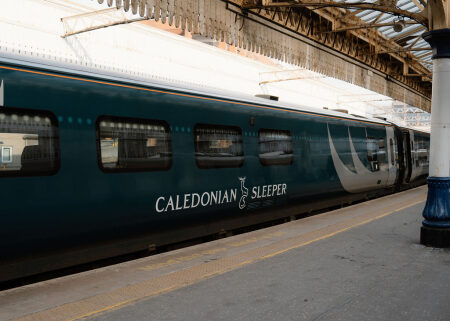 Caledonian Sleeper carriage waiting at a station platform under a glass roof