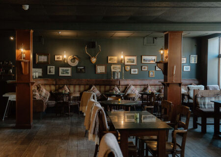 The Balmoral Arms' dining room, dark walls hung with pictures above tartan banquettes.